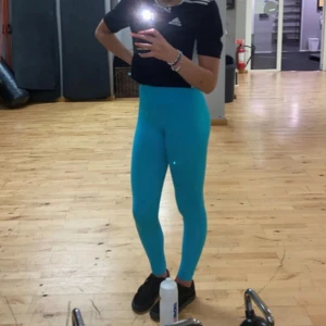 Turkosa höga leggings - Säljer ett par turkosa leggings med hög midja. De är tighta och sitter snyggt på kroppen, perfekta för gymmet eller annan träning. Materialet är stretchigt och bekvämt, vilket gör dem lätta att röra sig i.