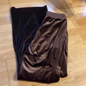 Bruna sammetsbyxor från SHEIN M - Mysiga bruna sammetsbyxor från SHEIN i storlek M. Byxorna har resår i midjan och är gjorda i ett glansigt, mjukt material som känns riktigt skönt mot huden. Perfekta för chill dagar eller när du vill ha en avslappnad look.