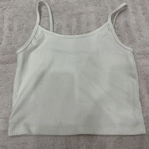 Ljusgrön ribbad linnetopp - Supersöt ljusgrön linnetopp med smala axelband och ribbad struktur. Perfekt för varma dagar och enkel att matcha med jeans eller kjol. Snygg och enkel design som passar till många olika stilar.