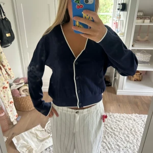 Mörkblå kofta från MNG med vita detaljer - Snygg mörkblå kofta från MNG i storlek S. Koftan har vita kanter längs v-ringningen och knäppningen. Den är stickad i ett mjukt material och har långa ärmar💕