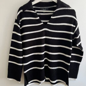 Randig svartvit stickad tröja Amisu - Snygg stickad tröja från New Yorker i svart med vita ränder. Tröjan har v-ringning, krage och långa ärmar. Perfekt för dig som gillar en chill och trendig look. 