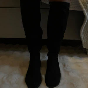 Svarta boots med låg klack - Snygga svarta stövlar/boots i mocka med spetsig tå och låg klack. Stövlarna går upp till knäna och har en stilren, klassisk look som passar till många outfits. Aldrig använda!