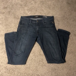 Replay jeans i mörkblå denim, W32 L32 - Snygga mörkblå jeans från Replay i klassisk femficksmodell. Jeansen har raka ben och normal passform, med diskreta slitningar för en cool look. Tillverkade i mjuk denim med dragkedjegylf och Replay-logga på fickan.