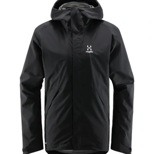 Svart regnjacka från Haglöfs - Svart regnjacka från Haglöfs med minimalistisk design och huva. Jackan har diskret logga på bröstet, dragkedja framtill och praktiska fickor. Perfekt för blöta dagar när du vill hålla dig torr och snygg.