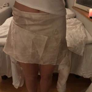 Kjol  - Superfin kjol med en ”smutsig” beige design. Även två tygbitar som hänger ner