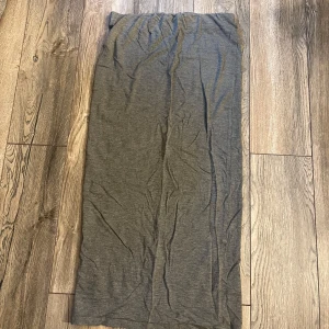 Mörkgrå långkjol i bomull - Enkel och stilren mörkgrå långkjol i mjukt bomullstyg. Kjolen har rak passform och är perfekt för dig som gillar minimalistisk stil. Passar till sneakers eller boots för en chill look.