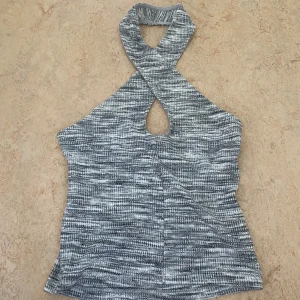 Fest topp - Orginalpris 199kr. Superfin  halterneck topp från gina tricot i mixade toner av grått och vitt. Toppen har korsade axelband och är ärmlös med en snygg, lite croppad passform. Aldrig använd💕