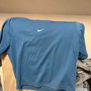 Blå Nike t-shirt  - Blå t-shirt från Nike med klassisk vit swoosh-logga på bröstet. Modellen är slim fit och har korta ärmar. Tillverkad i mjuk bomull som känns skön mot huden. Perfekt för dig som gillar sportig och clean stil.