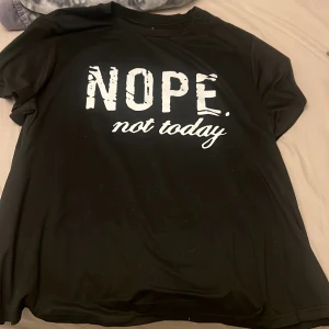 Svart t-shirt med tryck från Stmove Curve - Svart t-shirt från Stmove Curve i storlek 1XL med stort vitt tryck på bröstet där det står 'NOPE. not today'. Tillverkad i mjuk polyesterblandning med korta ärmar och rund hals. Perfekt för chill dagar när man vill göra ett statement.