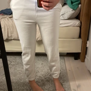 Vita mjukisbyxor med resår - Säljer ett par vita mjukisbyxor med resår i bensluten och midjan. De är riktigt sköna och perfekta för chill dagar hemma eller när du vill ha en avslappnad stil. Byxorna har en enkel design och är gjorda i mjukt material.