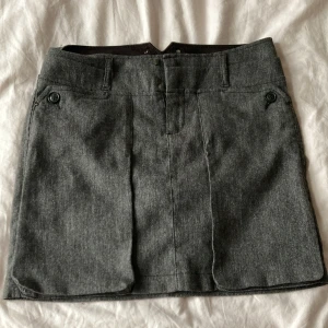 Lågmidjad kjol - Lågmidjad minikjol från Mexx i kostym material. Midja rakt över ca 37,5cm, längd ca 40cm