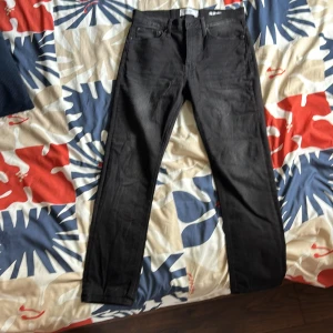 Svarta jeansbyxor från Les Deux - Säljer ett par svarta jeansbyxor från Asket med klassisk femficksdesign och raka ben. Jeansen har bälteshällor, knappgylf och är tillverkade i ett slitstarkt bomullstyg. Perfekta för dig som gillar en clean och stilren look.