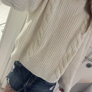 Vit stickad kabeltröja - Supermysig vit stickad tröja med grova kabelstickade detaljer längs ärmar och fram. Tröjan har en loose fit och ribbade muddar vid hals, ärmslut och nederkant. Perfekt att slänga på sig när det är kyligt ute. Har ingen lapp med storlek men passar M.🤍