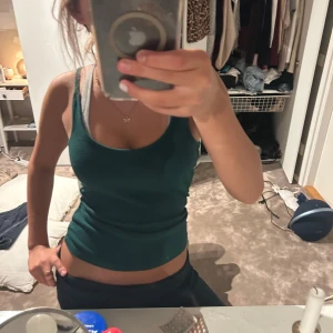 Mörkgrön ribbad linnetopp BikBok XS - Snygg mörkgrön ribbad linnetopp från BikBok i storlek XS. Modellen är croppad med smala axelband och har en figurnära passform. Perfekt att styla med jeans eller kjol för en chill look.