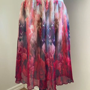 Plisserad blommig midikjol med resårmidja - Plisserad kjol med underbart mönster. Kjolen har en bekväm resår i midjan och underkjol. Mycket fint skick! 