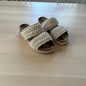 Beige virkade sandaler från So All - Säljer ett par snygga sandaler från So All i beige med två breda virkade remmar. Skorna har en platt sula och öppen tå, perfekta för varma dagar. Superfina att matcha till sommarens outfits!