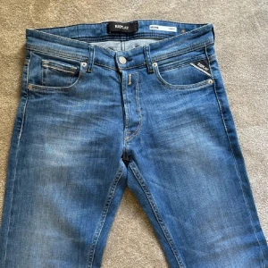 Blå Replay jeansbyxor - Säljer ett par klassiska blå jeans från Replay. Byxorna har normal passform och raka ben. Märkeslapp bak i midjan och diskreta detaljer vid fickorna. Perfekta för en avslappnad stil.