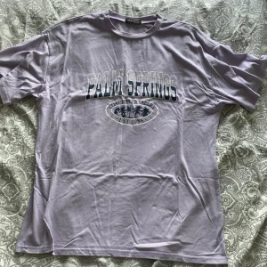 Ljuslila t-shirt med tryck från SHEIN - Ljuslila t-shirt från SHEIN med trycket 'Palm Springs Coachella Valley EST 1986' framtill. Klassisk passform med rund hals och korta ärmar. Perfekt för en avslappnad stil.
