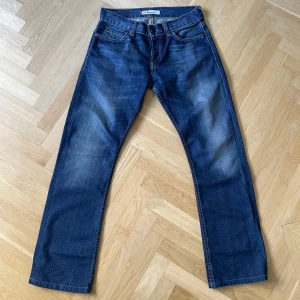 Levis 512 Bootcut Jeans Blå - Klassiska blå Levis 512 bootcut jeans med fem fickor och dragkedja. Jeansen har en något utsvängd passform nertill och är tillverkade i slitstarkt denim. Perfekta för dig som gillar en tidlös och avslappnad stil.