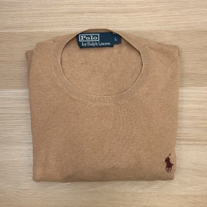 Ralph Lauren Stickad Tröja Beige M - L på etiketten men passar M. Säljer en klassisk beige tröja från Polo Ralph Lauren i 100% pima bomull. Tröjan har inga anmärkningar eller fläckar (bara veck på bild 2 och 3, inga skavanker). Tröjan har rund halsringning, lång ärm och den ikoniska broderade loggan på bröstet. Perfekt för dig som gillar stilrena och tidlösa plagg.