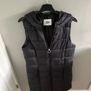  Dunväst  - En lite längre dunväst i mycket bra skick! Står tyvärr ingen storleks lapp i den men skulle säga att den är en xs!😇Den är 82 cm lång och har en omkrets på 90cm. 