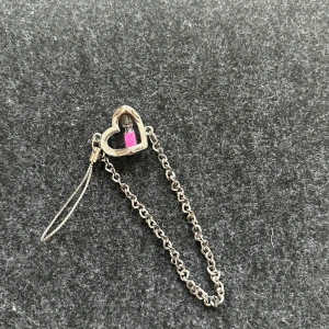 Silverfärgat hängare med hjärta och timglas - Säljer ett silverfärgat hängare med en kedja och ett hjärta. I hjärtat finns en liten rosa timglas som ger en söt touch. Perfekt som accessoar till din stil.