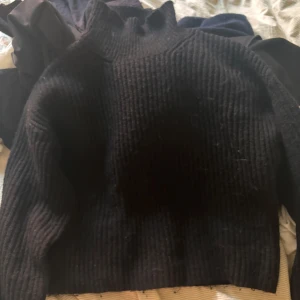 Svart stickad polotröja från Gina Tricot - Mysig svart stickad polotröja från Gina Tricot. Tröjan har en hög polokrage och är ribbstickad med långa ärmar. 