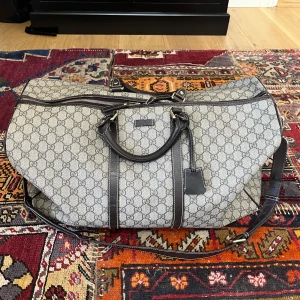 Gucci weekend väska (duffle bag) - Stilren axelväska från Gucci i beige med klassiskt GG-monogram och mörkbruna skinn-detaljer. Väskan har både handtag och justerbar axelrem samt dragkedja upptill. Perfekt för resor eller gymmet. Nypris: 30k , lika stor som lv keepall 50 
