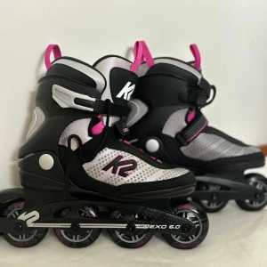 Svarta och rosa inlines från K2 - Säljer ett par coola inlines från K2 i svart och rosa. De har en robust design med snörning och spänne för extra säkerhet. Perfekta för en aktiv livsstil och att rulla runt i parken med stil. Ny pris från zalando 1800, går inte att köpa just dessa längre