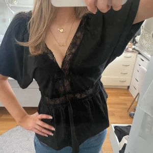 Svart blus med spetsdetaljer - Snygg svart blus med v-ringning och spetsdetaljer, köpte secondhand och har ingen lapp så vet inte märke 💗💗🤗