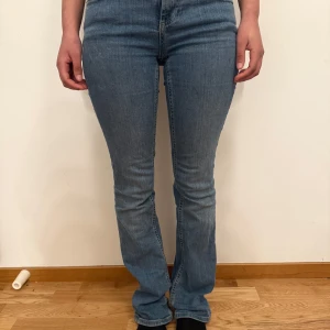 Blå jeans med bootcut - Snygga blå jeans med bootcut-stil och medel midja. Perfekta för en avslappnad look. De har en klassisk design med dragkedja och knapp framtill. Köpta på Zara för 500 kr! 