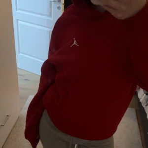 Röd hoodie från Jordan - Säljer en helt oanvänd röd hoodie från Jordan. Hoodien har en stor ficka framtill och är perfekt för en sportig look. Passar bra till både träning och vardag.