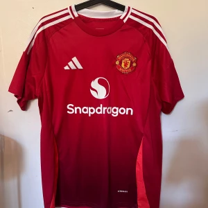 Röd Manchester United tröja 24/25 - Säljer en röd Manchester United tröja från denna säsong. Använd 1-2 gånger, säljer den för att den var för stor. Garnacho på ryggen
