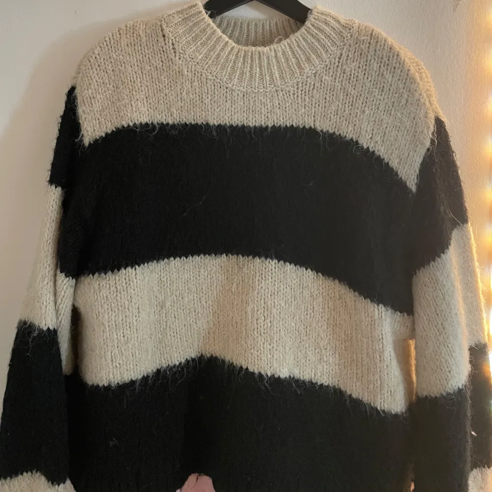 Mysig stickad tröja från Gina Tricot i svart och beige. Tröjan har ett randigt mönster och långa ärmar, perfekt för kyliga dagar. Den har en rund halsringning och är gjord i ett mjukt material som håller dig varm.. Neuletakit & Villapaidat.