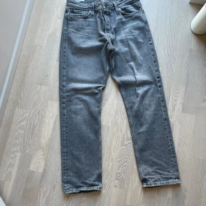 Grå jeansbyxor - Snygga grå jeansbyxor . De har en rak passform och är perfekta för en avslappnad stil. Byxorna har en knappgylf och är tillverkade i ett slitstarkt material. Köpta för ca 1000kr. Bra skick, 150kr + frakt