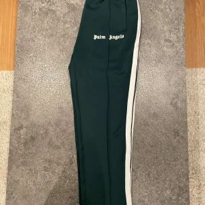 Svarta byxor från Palm Angels - Snygga svarta byxor från Palm Angels med vita sidoremsor och logotyp på sidan. Perfekta för en stilren och avslappnad look. Byxorna har en normal passform och är tillverkade i ett bekvämt material.