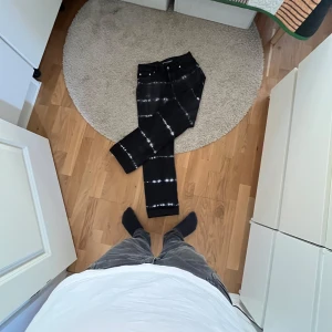 Svarta jeans med batikmönster från Junkyard - Snygga svarta jeans med ett coolt batikmönster från Junkyard. De har en klassisk femficksdesign och en bekväm passform. Perfekta för att ge din outfit en unik touch.