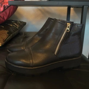 Svarta boots med dragkedja - Snygga svarta boots i skinn med dragkedja på sidan. De har en stilren design med en lätt textur på baksidan som ger en extra touch. Perfekta för både vardag och mer uppklädda tillfällen.