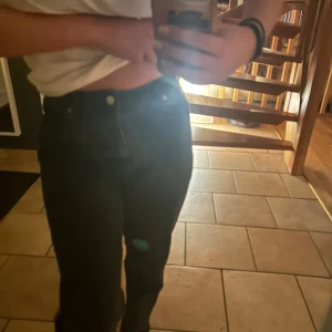 Svarta Mom jeans - Snygga svarta jeans med hög midja och klassisk design. De har en rak passform och är perfekta för en stilren look. Jeansen har fickor både fram och bak samt en knapp och dragkedja framtill.