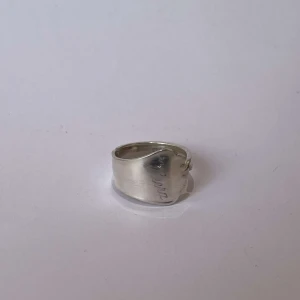 Silverring med gravyr - Elegant silverring med en subtil gravyr på ytan. Ringen har en bred design som ger ett stilrent och modernt intryck. Perfekt för att lägga till en touch av elegans till din stil.