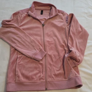 Rosa fleecejacka från Sportchek - Mysig rosa fleecejacka från Sportchek med dragkedja framtill. Jackan har långa ärmar och ribbade muddar vid ärmslut och nederkant. Perfekt för kyliga dagar!