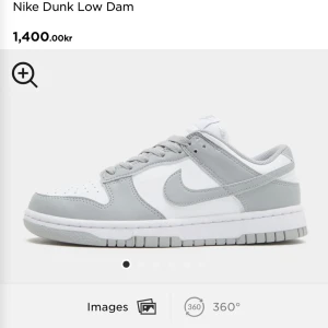 Nike Dunk Low Dam - Snygga Nike Dunk Low sneakers i en stilren kombination av vitt och grått. Skorna har en klassisk design med snörning och den ikoniska Nike-loggan på sidan. Perfekta för en casual look. 