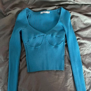 Blå ribbad topp från NAKD - Säljer en snygg blå ribbad topp från NAKD som knappt är använd. Skriv för fler bilder!