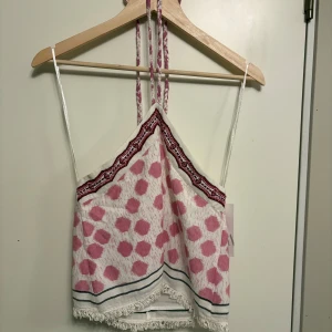 Rosa och vit prickig linnetopp från Zara - Säljer en söt linnetopp från Zara i storlek XS. Toppen har rosa prickigt mönster, tunna axelband och knyt i nacken. Dekorativa band och fransdetalj nedtill. Perfekt för varma dagar! Dessutom aldrig använd, prislapp sitter kvar.