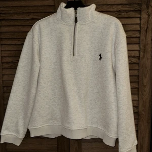 Vit med mörkare detaljer halvzip sweatshirt från Ralph Lauren - Säljer en vit sweatshirt från Ralph Lauren med halv dragkedja och hög krage. Storlek S men den är väldigt liten för storleken. Har du XS passar den förmodligen bättre