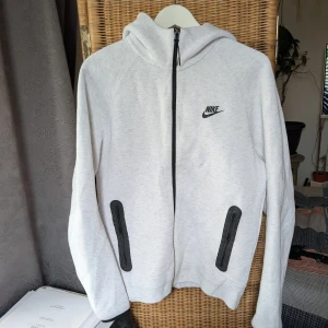 Vit/grå Nike tech gen 4 - Ljusgrå hoodiejacka från Nike med svart dragkedja och svart logotyp. 