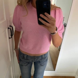 Rosa stickad kortärmad tröja - Söt rosa stickad tröja med korta puffärmar och rund hals. Storlek XS men passar S också. Super lent tyg, inga tecken på att den ens används, nytt skick! Använd ca 2-3 ggr.
