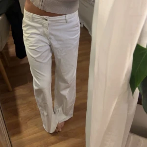 Vita vida byxor - Säljer ett par vita byxor med normal passform och vida ben. Byxorna har klassisk knapp- och dragkedjestängning samt fickor fram och bak. Perfekta för en clean och fräsch look.