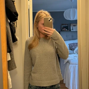 Grå stickad tröja - Säljer en enkel och stilren grå stickad tröja med rund halsringning. Tröjan har långa ärmar och en klassisk passform som funkar till det mesta