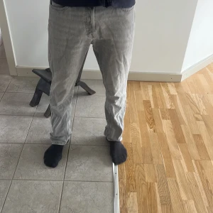 Grå jeans från Jack & Jones - Säljer ett par grå jeans från Jack & Jones med knäppning framtill. Klassisk femficksmodell i rak passform, perfekta till vardags. Snygg tvättad grå färg som passar till det mesta.